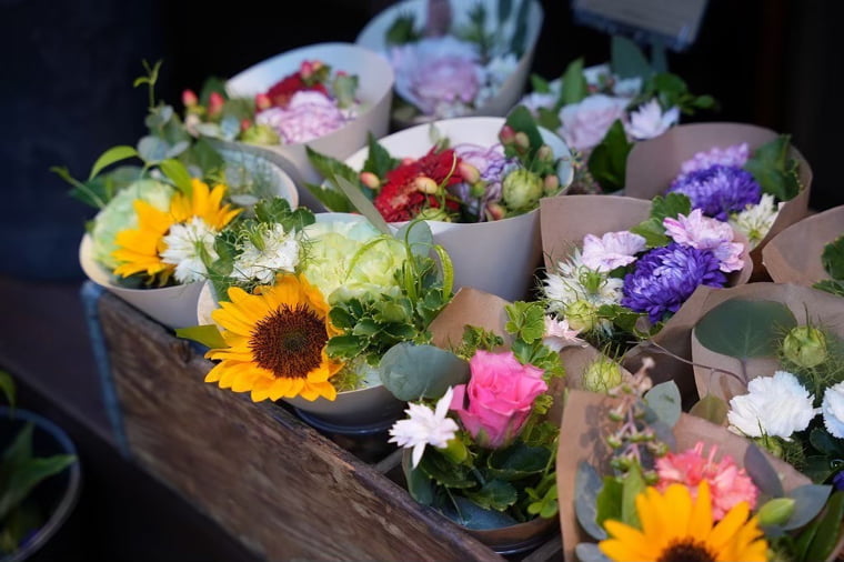 木箱に並べた色とりどりの花束の写真