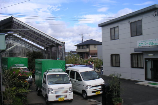 事業所の前に配送用の軽トラックが並ぶ写真