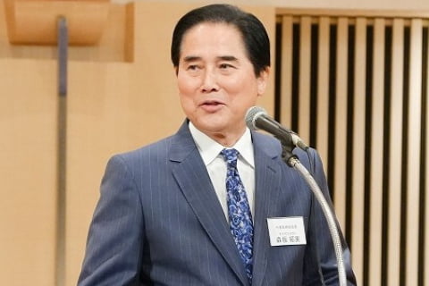 式典の演台であいさつをする代表取締役会長の写真