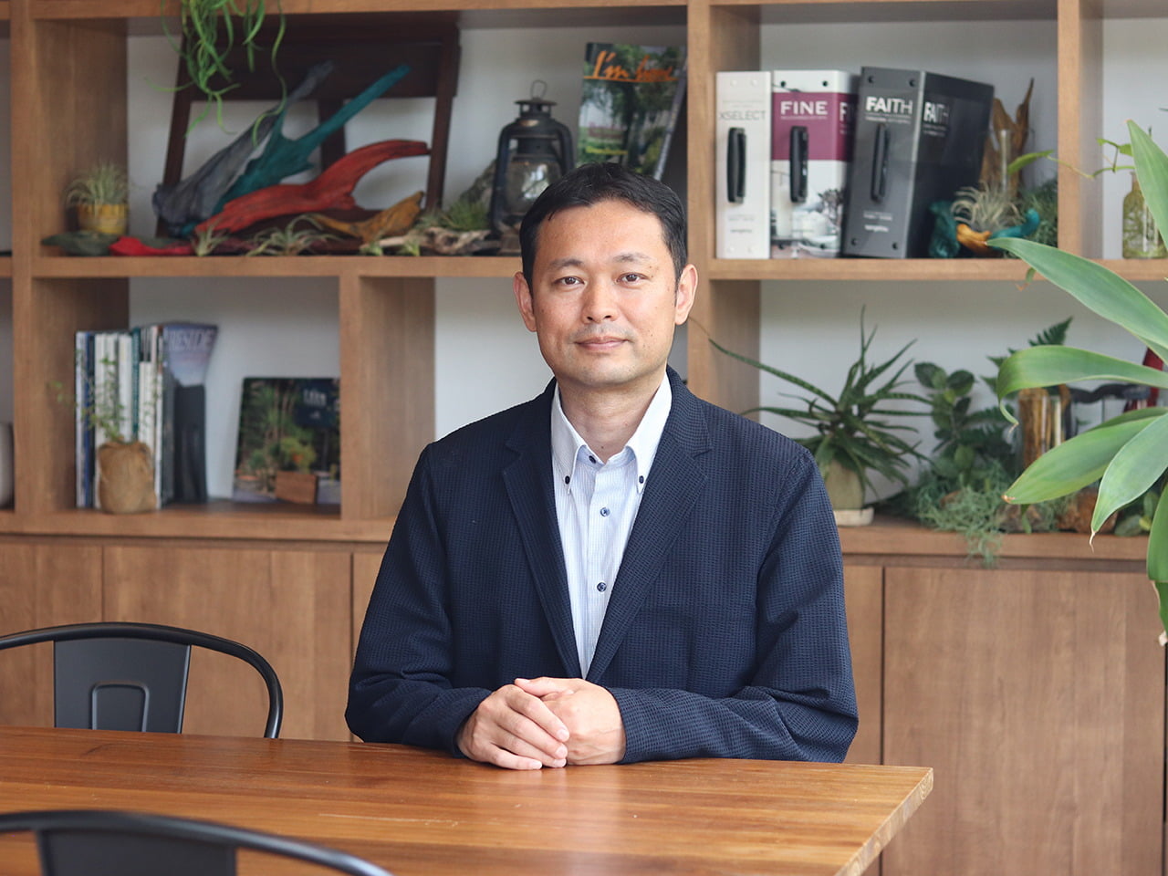 飾り棚を背にした机で正面を見る代表取締役社長の写真