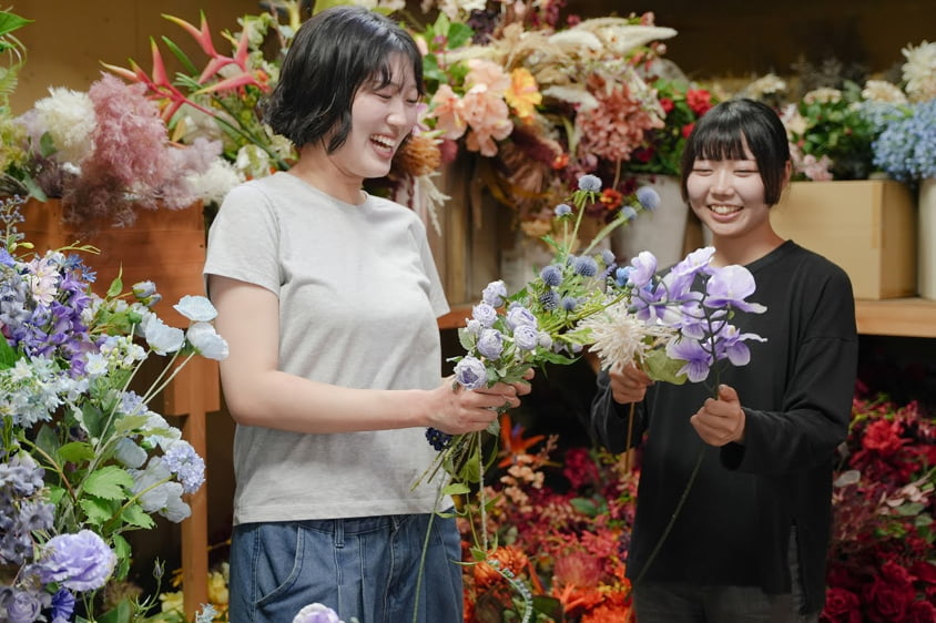 花に囲まれた店内で花束をつくる社員の写真