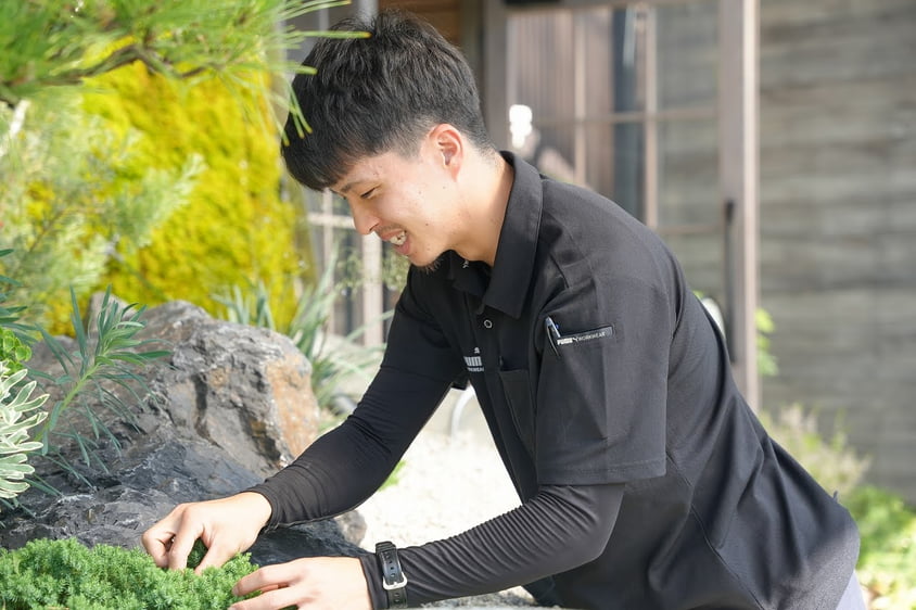 岩を組んだ植栽を手入れする社員の写真