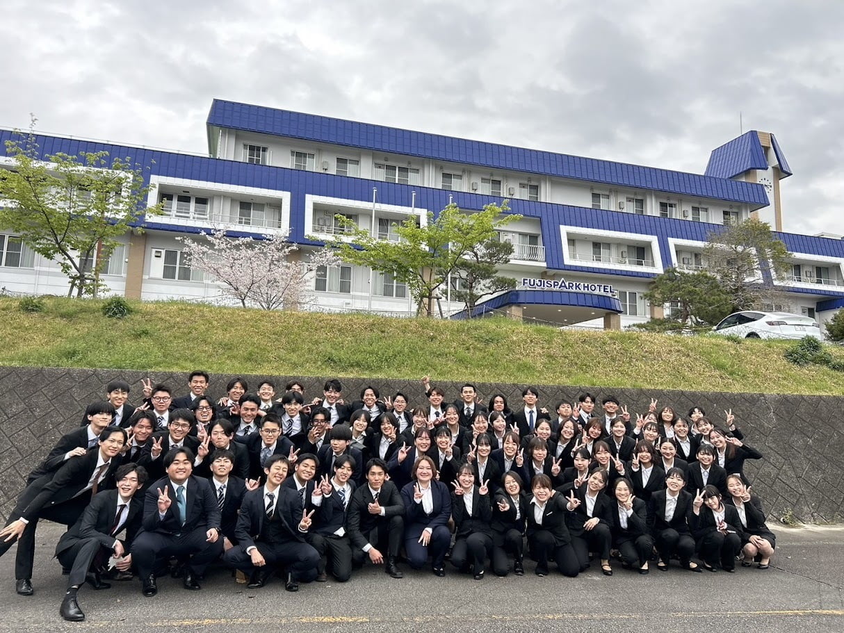 ホテルの前でスーツ姿の新入社員が並ぶ集合写真