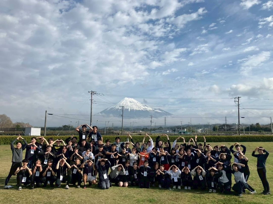 富士山を背景に芝生で記念撮影をする社員たちの写真