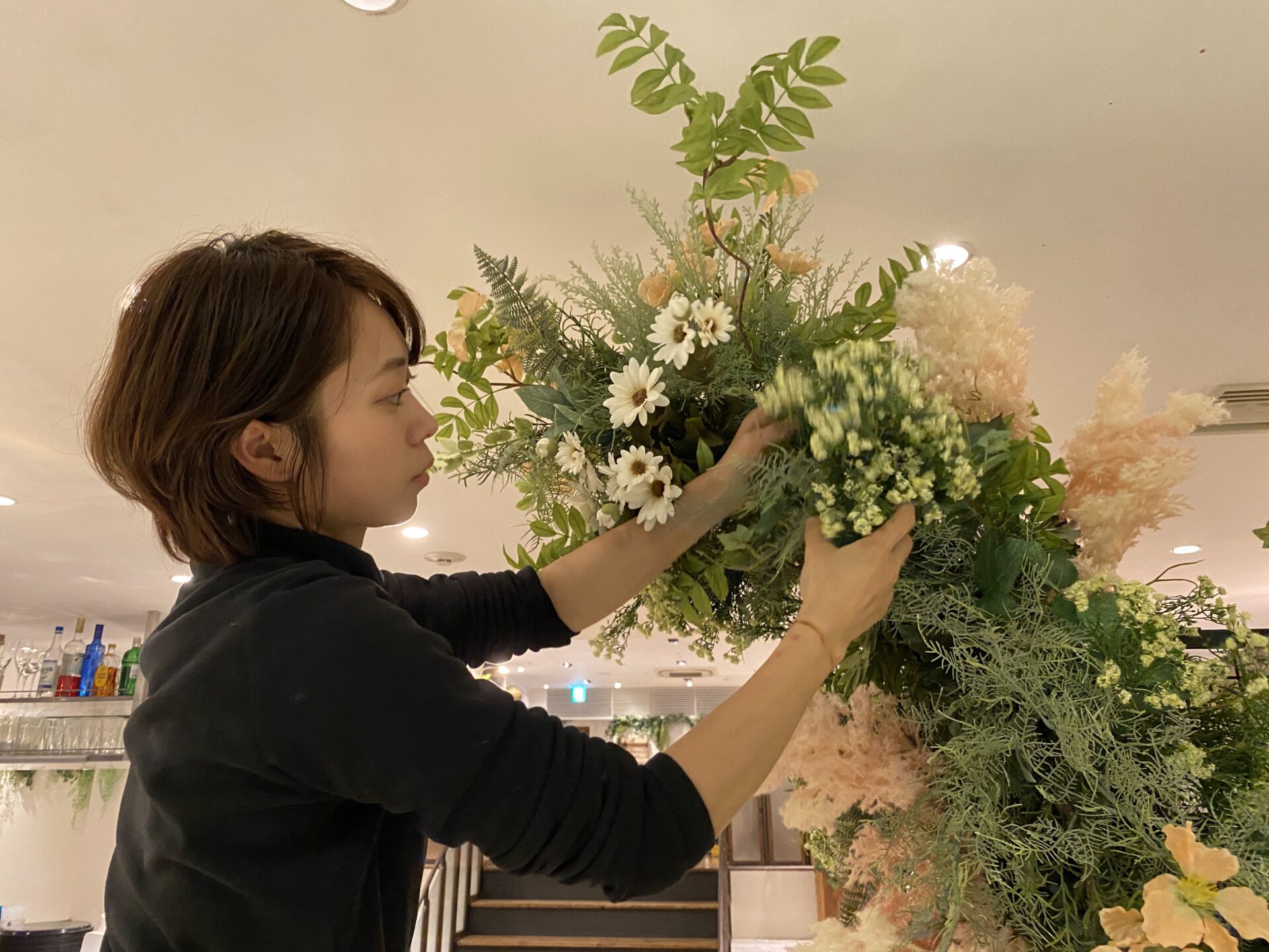 観葉植物を抱えて笑顔を見せる社員の写真