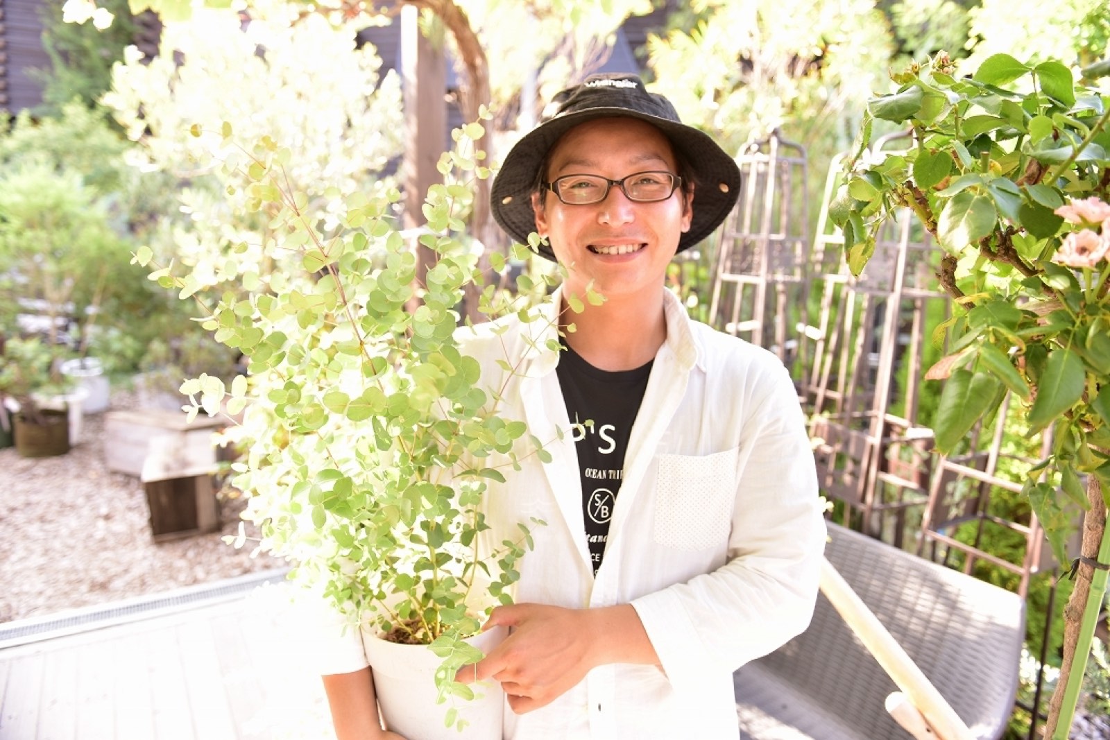 屋外で鉢植えのグリーンを抱えて笑う女性社員の写真