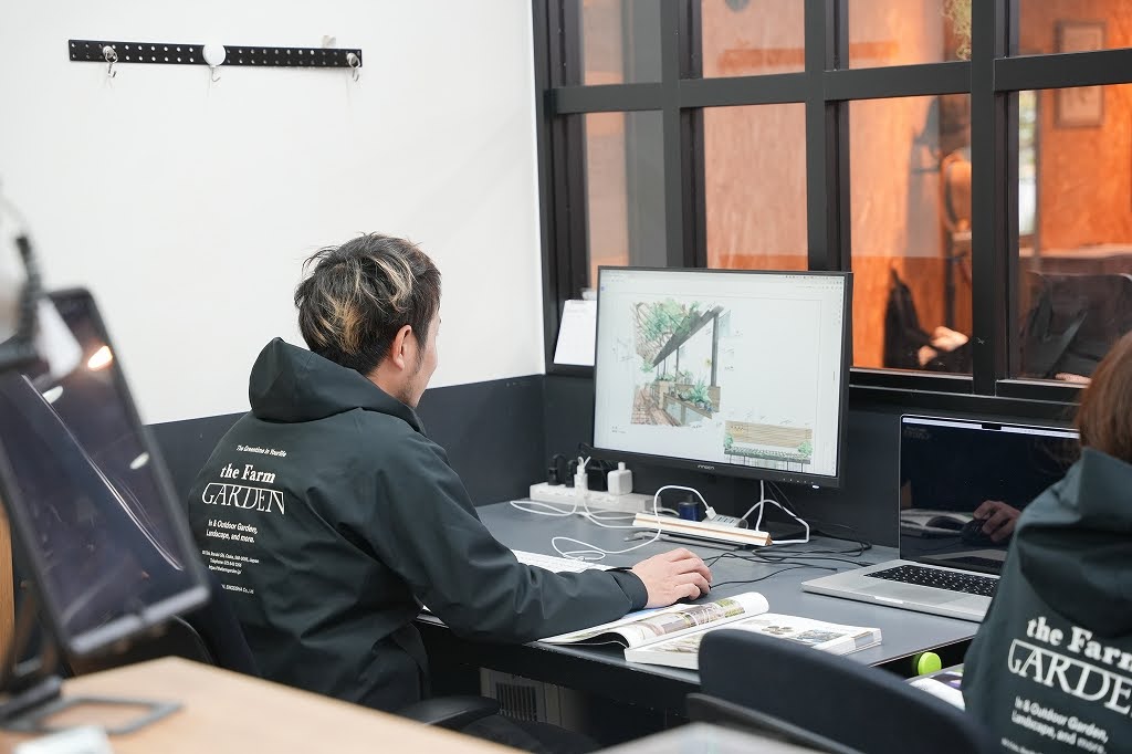 観葉植物を抱えて笑顔を見せる社員の写真